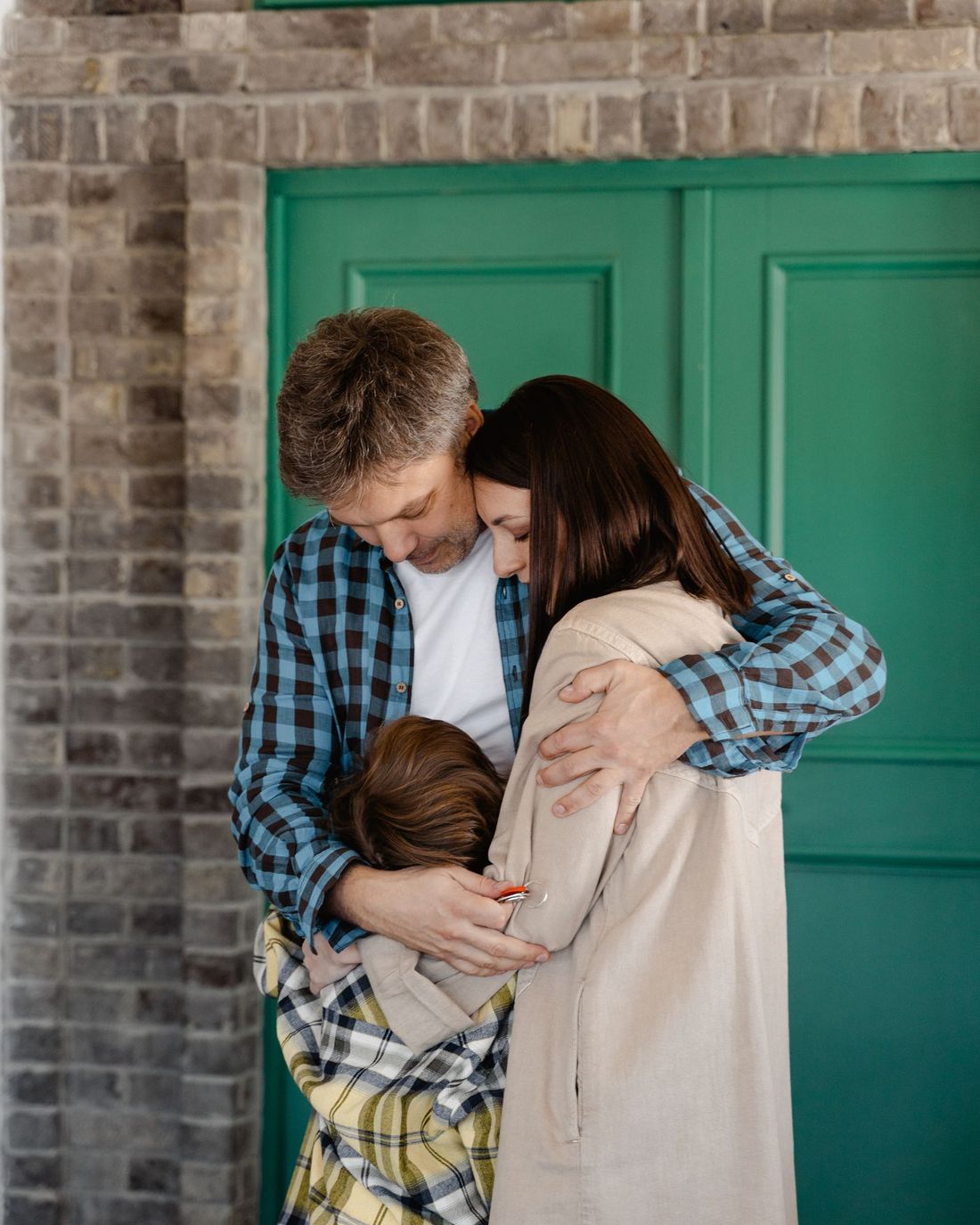 Parents hugging their child outside their home