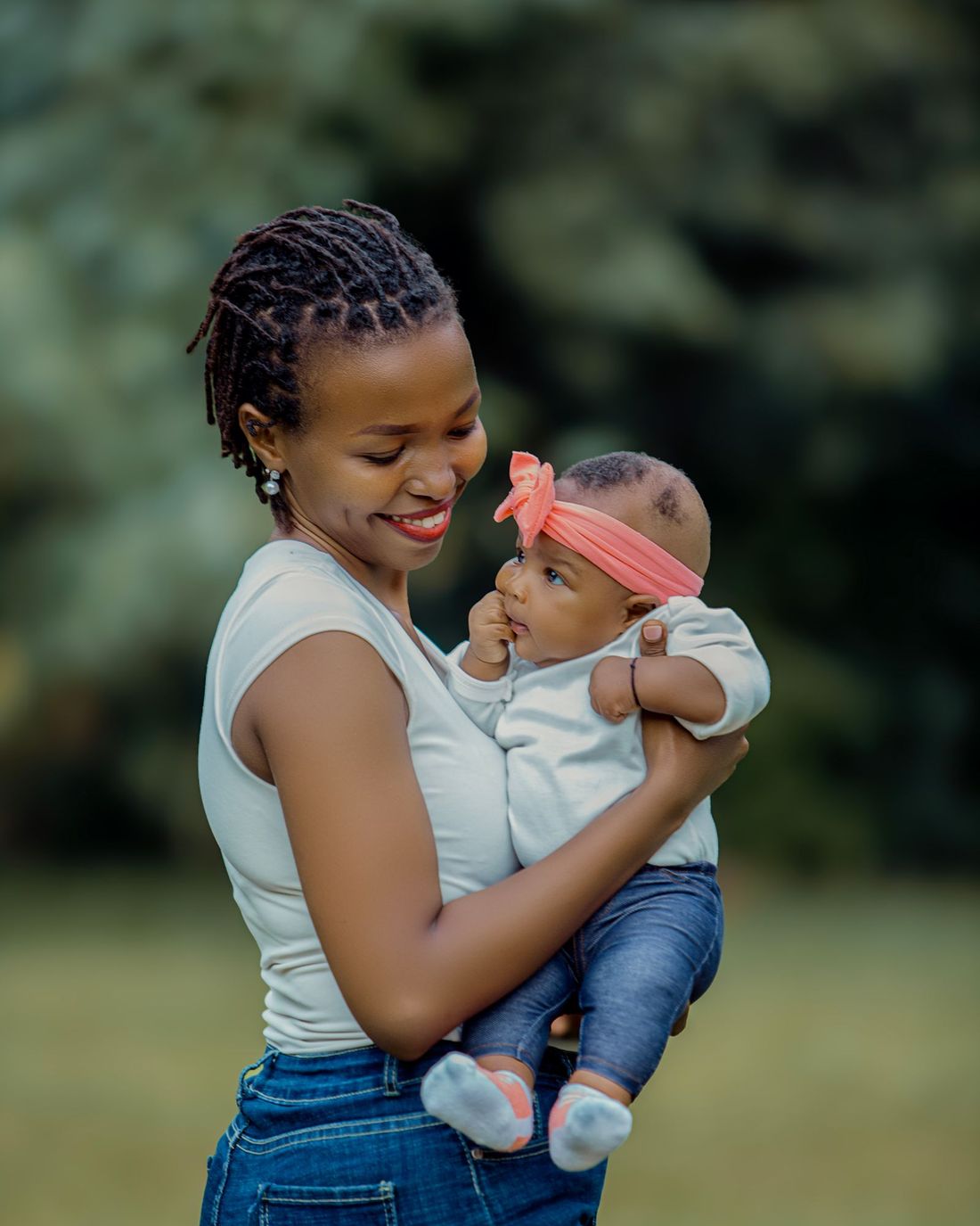 A smiling mother holding her baby outdoors